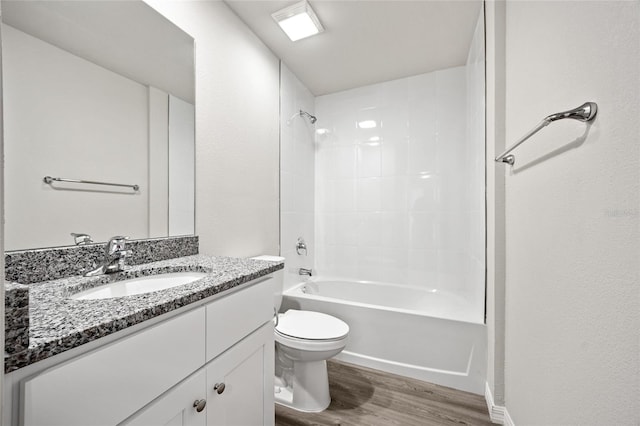 full bathroom with vanity, hardwood / wood-style floors, tiled shower / bath, and toilet