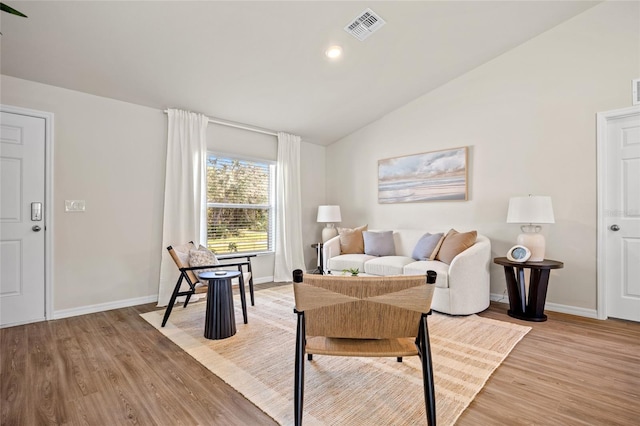 living room with light hardwood / wood-style floors and vaulted ceiling