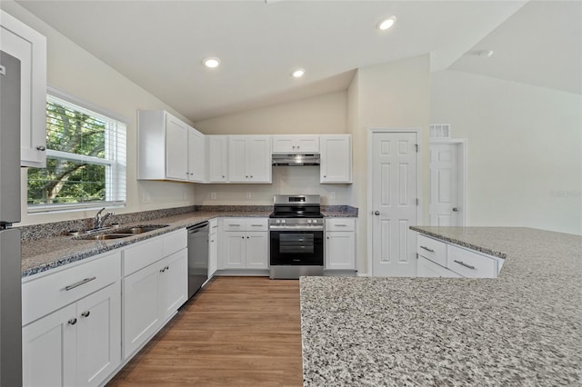 kitchen featuring light stone countertops, light wood-type flooring, stainless steel appliances, white cabinetry, and lofted ceiling