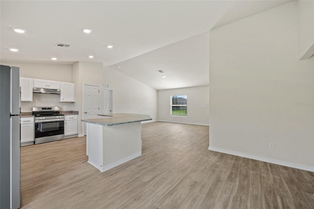 kitchen featuring appliances with stainless steel finishes, light wood-type flooring, light stone counters, vaulted ceiling, and white cabinetry