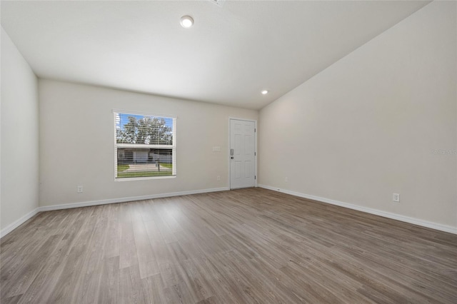 unfurnished room with light hardwood / wood-style floors and vaulted ceiling