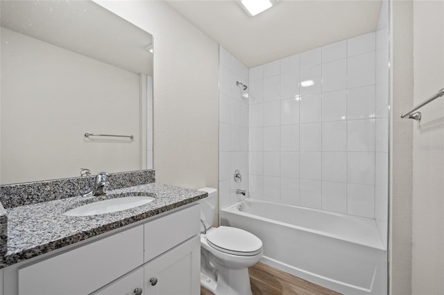 full bathroom featuring hardwood / wood-style floors, vanity, tiled shower / bath combo, and toilet