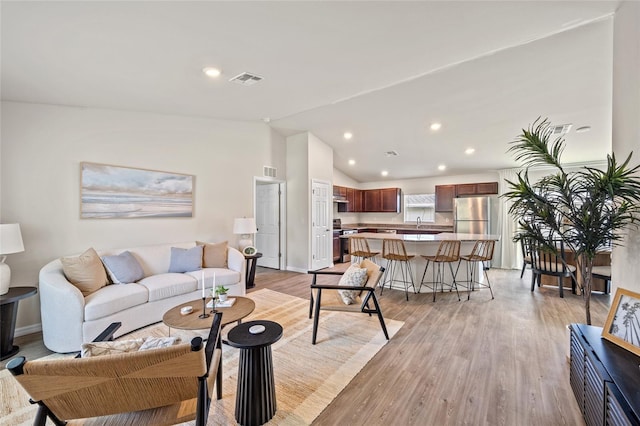 living room with light hardwood / wood-style flooring and vaulted ceiling