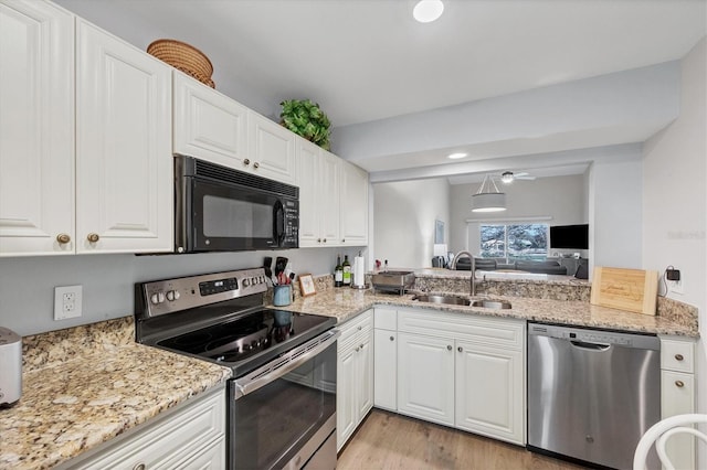 kitchen with light stone counters, appliances with stainless steel finishes, white cabinetry, light hardwood / wood-style floors, and sink