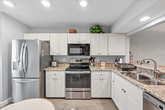 kitchen featuring light stone countertops, sink, light wood-type flooring, white cabinetry, and stainless steel appliances