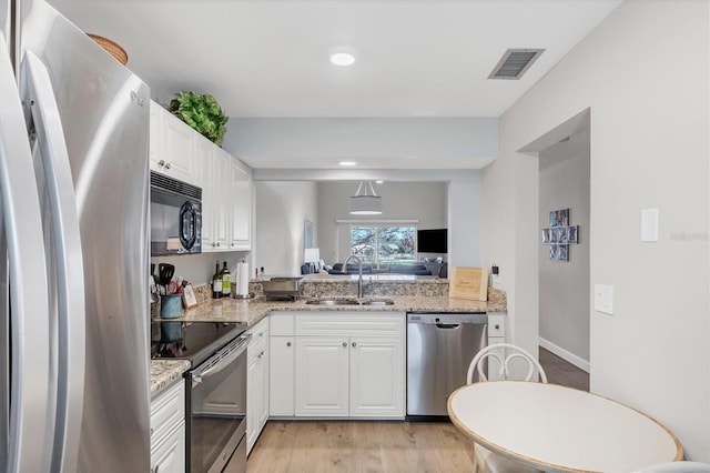 kitchen with light stone counters, white cabinetry, sink, light hardwood / wood-style floors, and stainless steel appliances