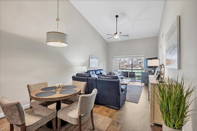 dining space with wood-type flooring, high vaulted ceiling, and ceiling fan