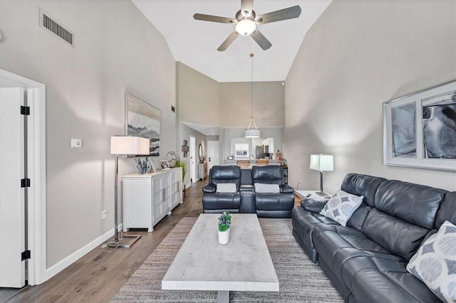 living room with hardwood / wood-style floors, high vaulted ceiling, and ceiling fan