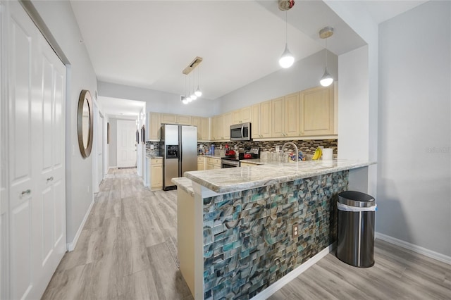 kitchen featuring pendant lighting, kitchen peninsula, appliances with stainless steel finishes, and light hardwood / wood-style floors