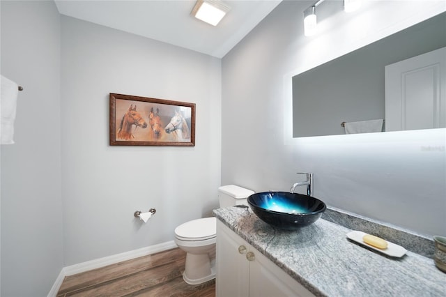 bathroom featuring toilet, vanity, vaulted ceiling, and hardwood / wood-style flooring