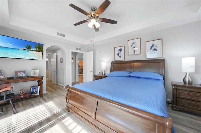 bedroom featuring hardwood / wood-style flooring, ceiling fan, and a raised ceiling