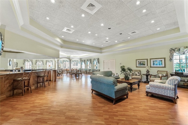 living room featuring ornamental molding, a tray ceiling, and light hardwood / wood-style floors