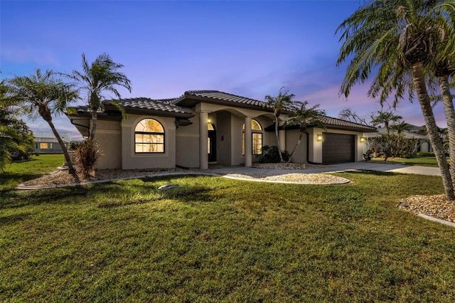 mediterranean / spanish-style house with a garage and a yard