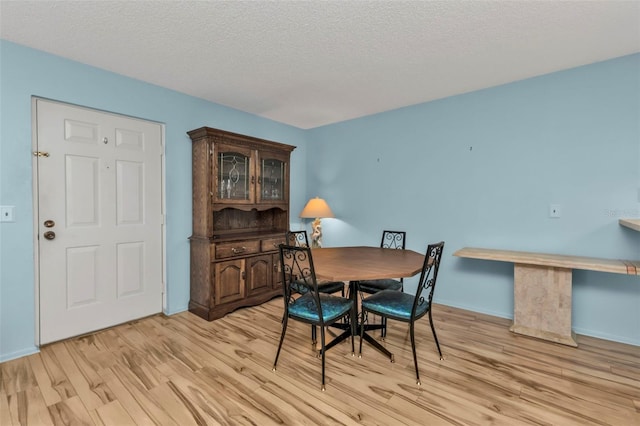 dining room with a textured ceiling and light hardwood / wood-style flooring