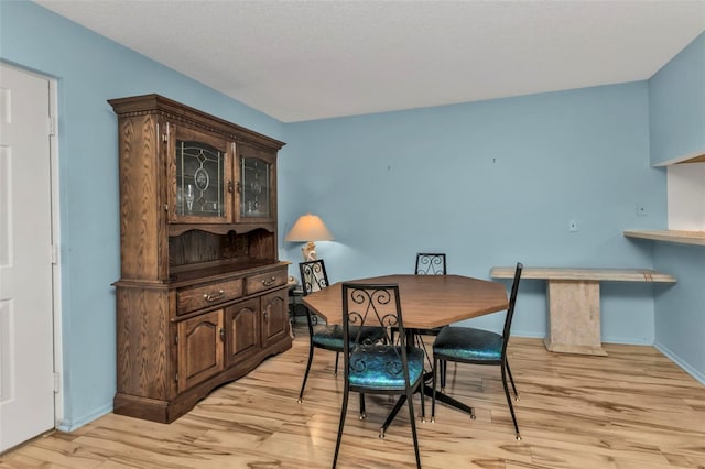 dining area with light wood-type flooring and a textured ceiling