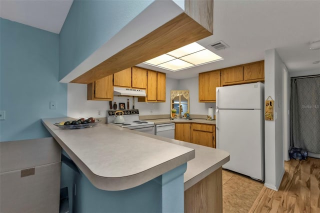 kitchen featuring kitchen peninsula, white appliances, light hardwood / wood-style floors, and sink