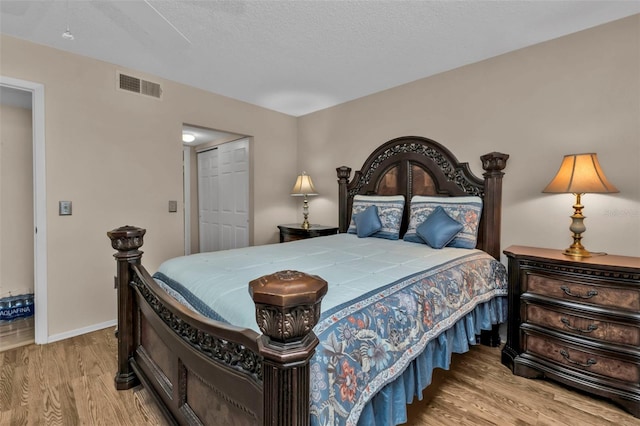 bedroom with a textured ceiling, light wood-type flooring, and a closet