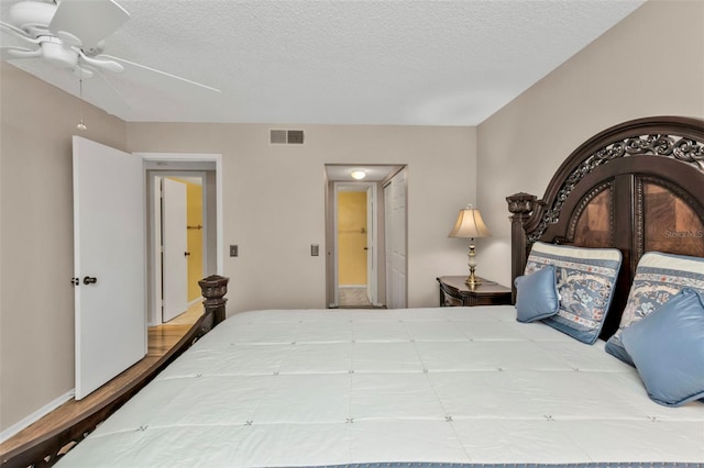 bedroom with ceiling fan, wood-type flooring, and a textured ceiling