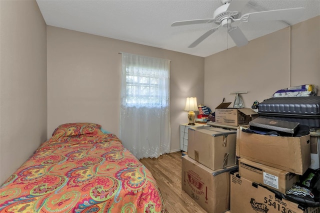 bedroom with ceiling fan, light hardwood / wood-style floors, and a textured ceiling