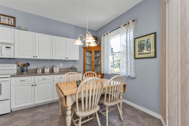 dining area with dark tile patterned floors and an inviting chandelier