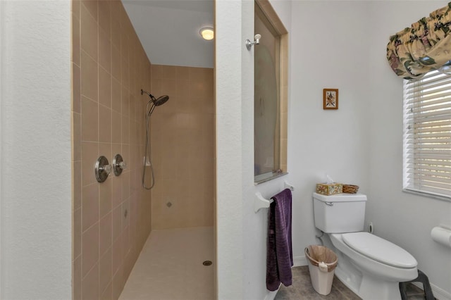 bathroom featuring a tile shower and toilet