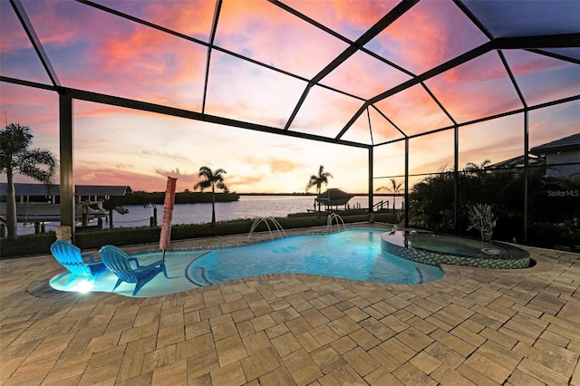 pool at dusk featuring glass enclosure, an in ground hot tub, a patio area, pool water feature, and a water view