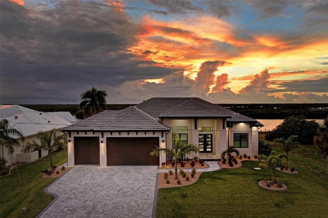 prairie-style home featuring a garage, a water view, and a yard