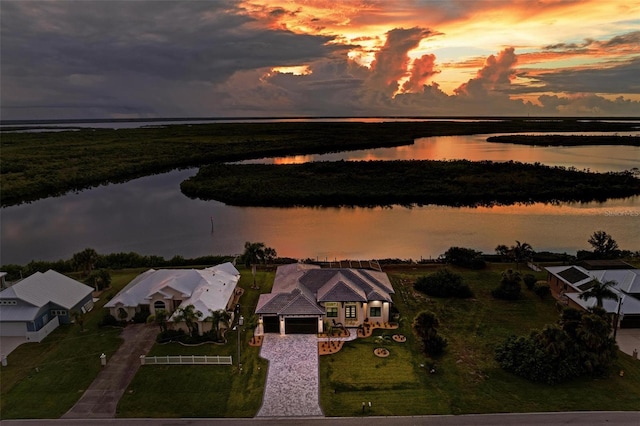 aerial view at dusk featuring a water view