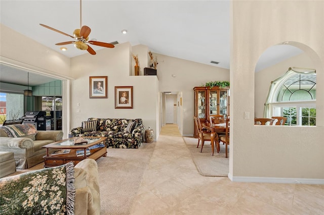 tiled living room with high vaulted ceiling, plenty of natural light, and ceiling fan