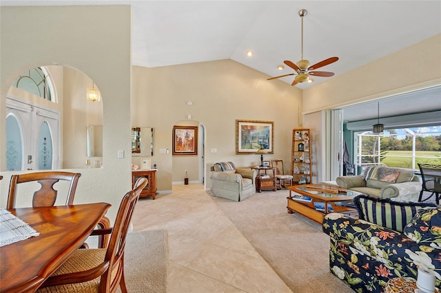 tiled living room with ceiling fan and high vaulted ceiling