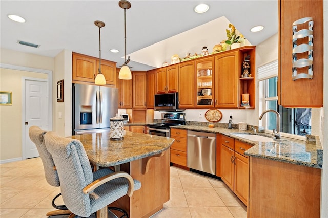 kitchen featuring stainless steel appliances, light stone counters, decorative light fixtures, and a kitchen island