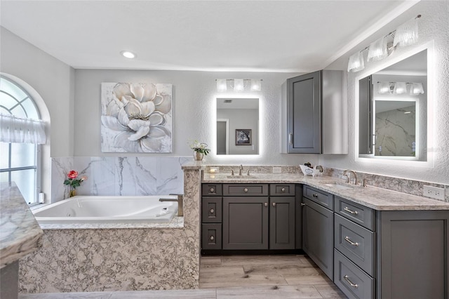 bathroom with vanity, hardwood / wood-style flooring, and a relaxing tiled tub