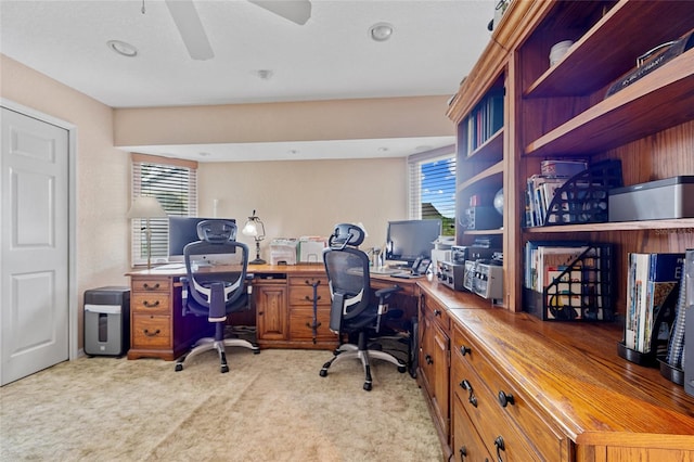 carpeted office with built in desk and ceiling fan