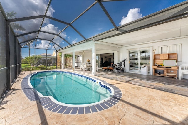 view of pool with glass enclosure, ceiling fan, and a patio area