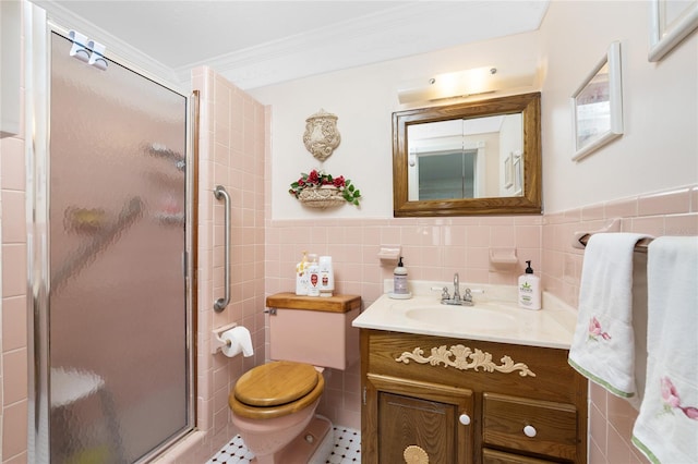 bathroom with a shower with door, vanity, tile walls, and ornamental molding