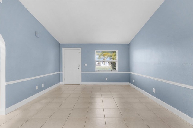 unfurnished room with light tile patterned flooring and vaulted ceiling