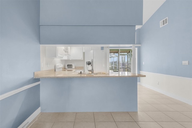 kitchen featuring white cabinetry, kitchen peninsula, white appliances, and light tile patterned floors