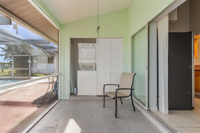 unfurnished sunroom featuring lofted ceiling and stacked washer and dryer