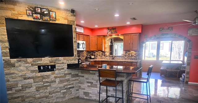 kitchen with kitchen peninsula, tasteful backsplash, a breakfast bar area, sink, and stainless steel appliances