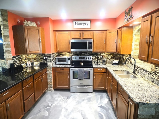 kitchen with light stone countertops, sink, appliances with stainless steel finishes, and backsplash