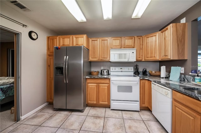 kitchen with white appliances, light tile patterned flooring, and dark stone counters