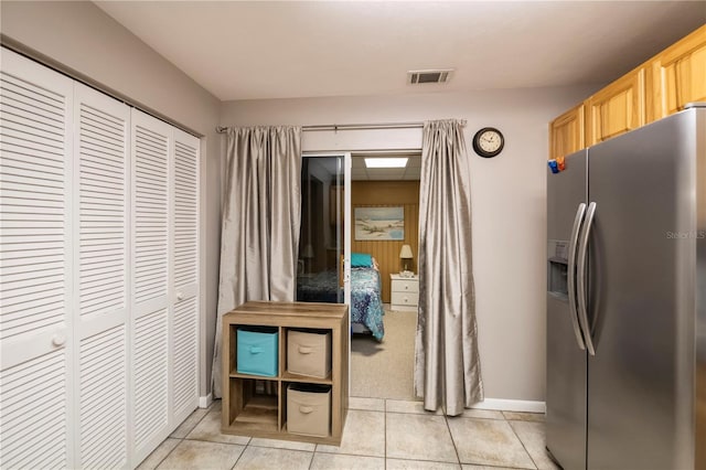 kitchen featuring stainless steel fridge, light brown cabinets, and light tile patterned floors