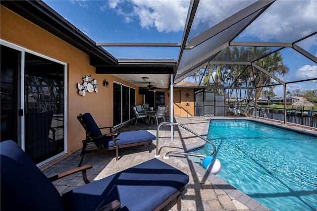 view of swimming pool featuring a patio area, ceiling fan, and glass enclosure