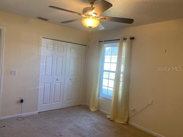 unfurnished bedroom featuring light colored carpet, a closet, and ceiling fan