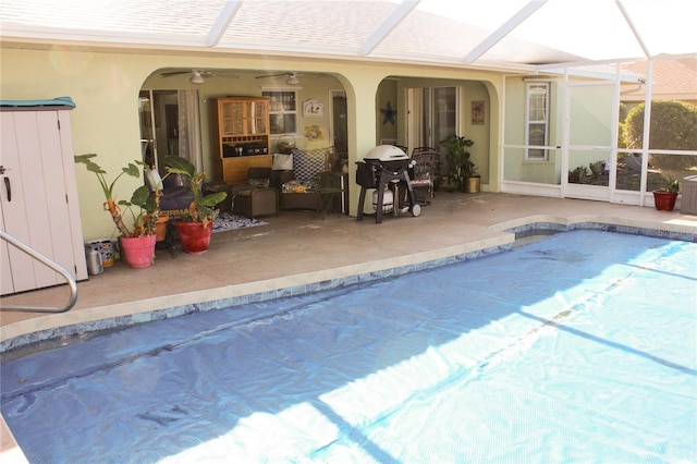 view of pool with a patio, glass enclosure, ceiling fan, and a grill