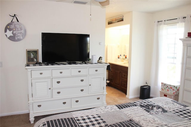 bedroom featuring connected bathroom and light colored carpet