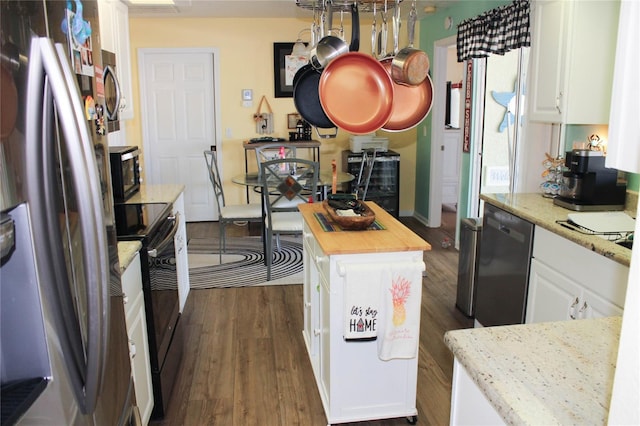 kitchen with stainless steel appliances, a center island, dark hardwood / wood-style floors, white cabinetry, and butcher block counters