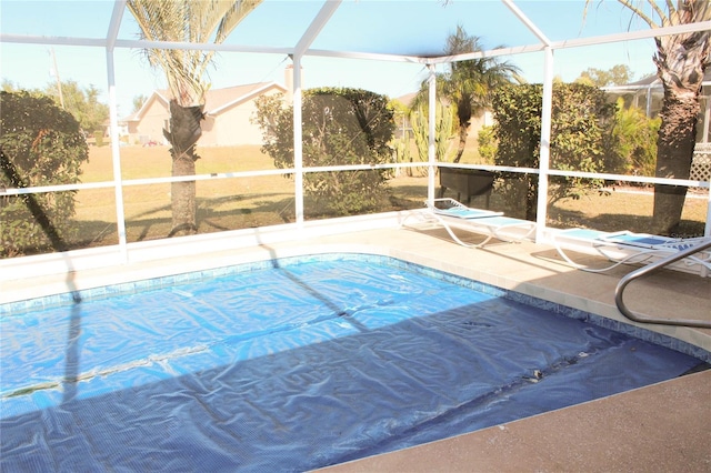 view of pool with glass enclosure and a patio