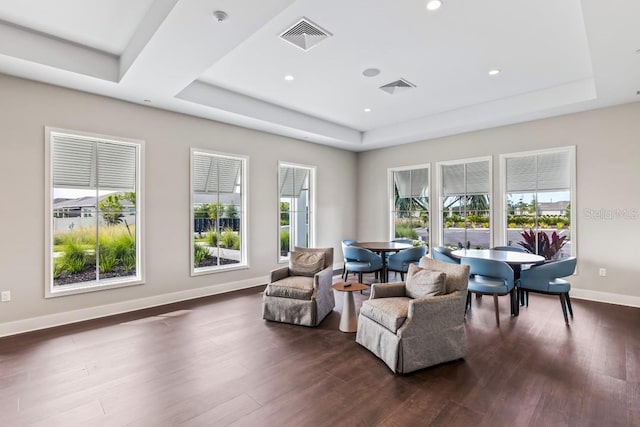 living area with dark wood-type flooring, a tray ceiling, and visible vents