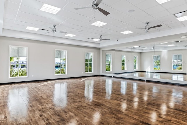 exercise room featuring wood finished floors, a ceiling fan, and baseboards